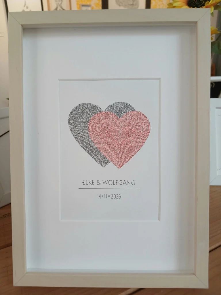 Framed wedding calligram of two overlapping hearts in black and red, written with the names of the couple, with names and date below