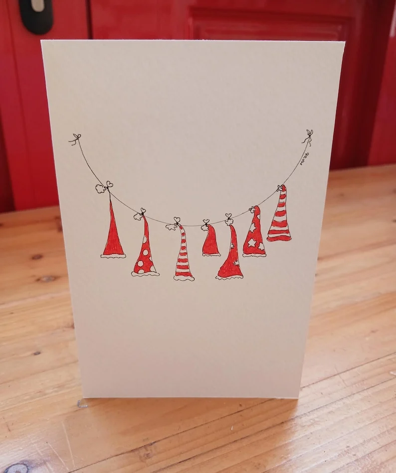 Hand-drawn Christmas card with red Christmas hats hanging on a washing line