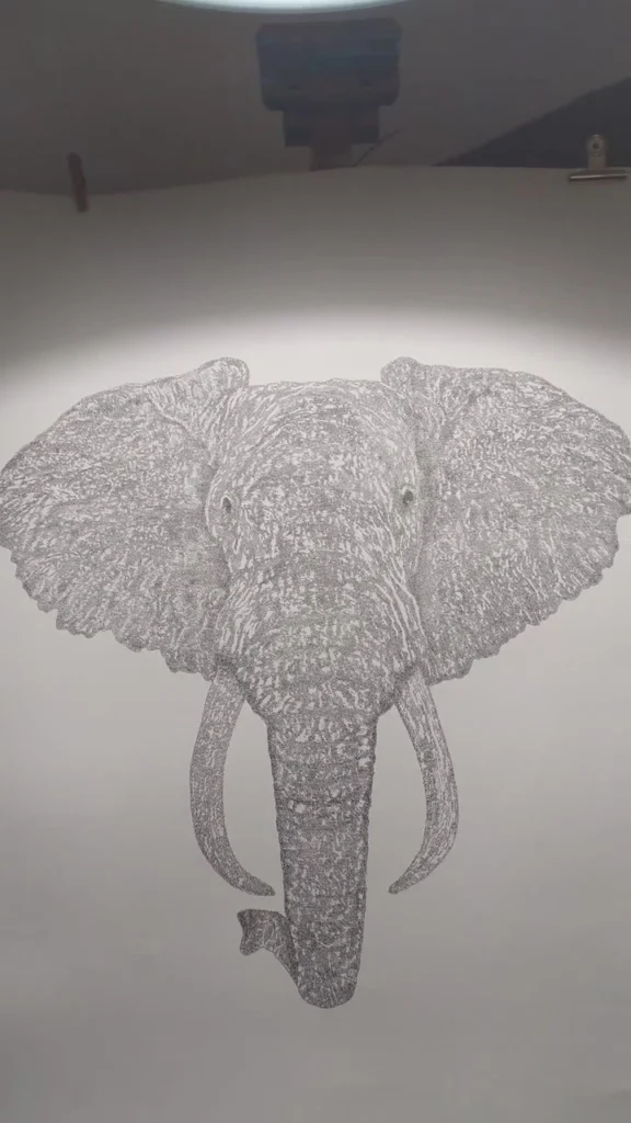 Calligram of an elephant with large ears and tusks, written with thousands of tiny words